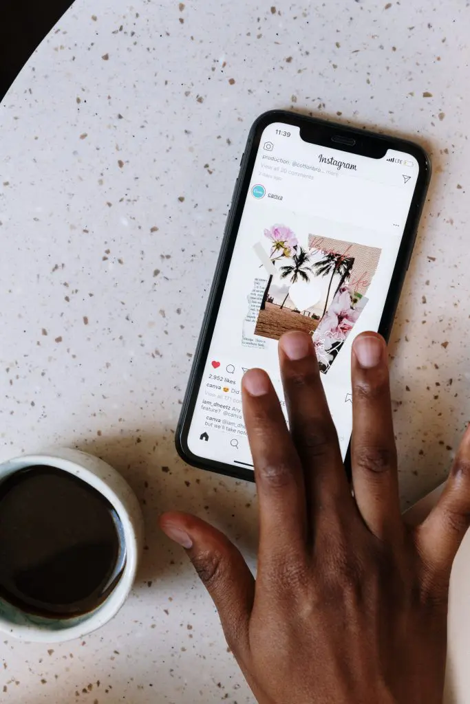 ¿Qué es el índice de popularidad en LinkedIn? 4 Mano de una mujer interactuando en Instagram, con un café a su lado.